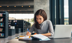 Female student studying with laptop in university library.