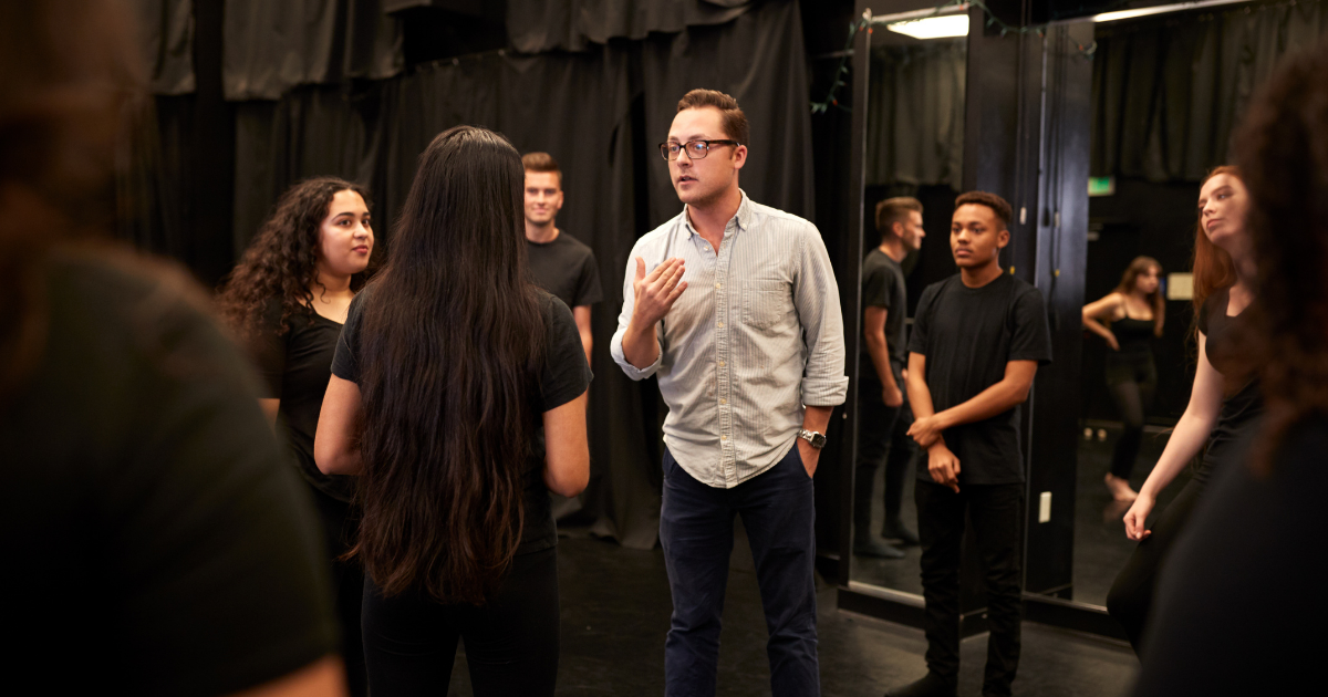 Teacher stands in the centre of a circle of students