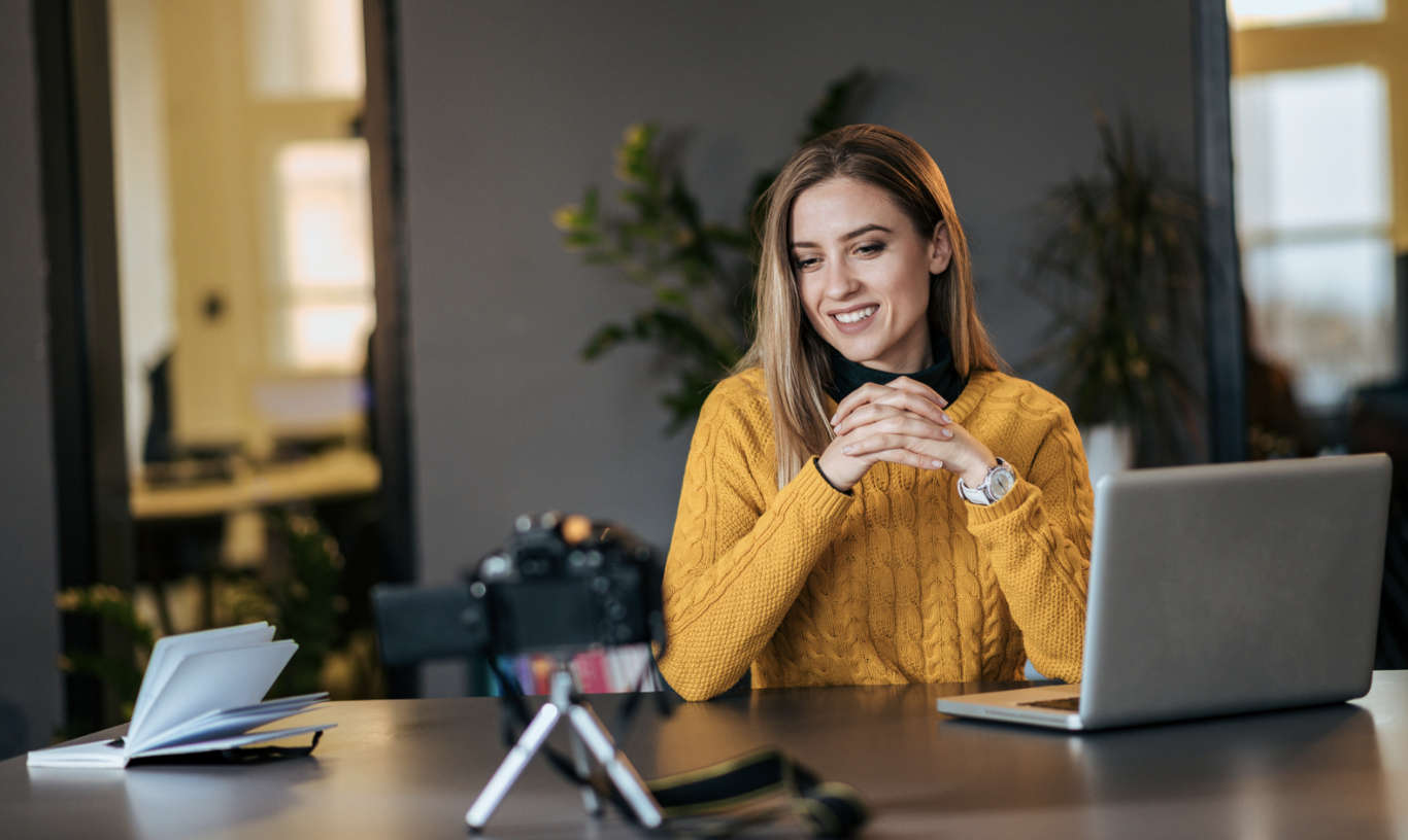 Teacher wearing yellow jumper looking at camera on a desk 