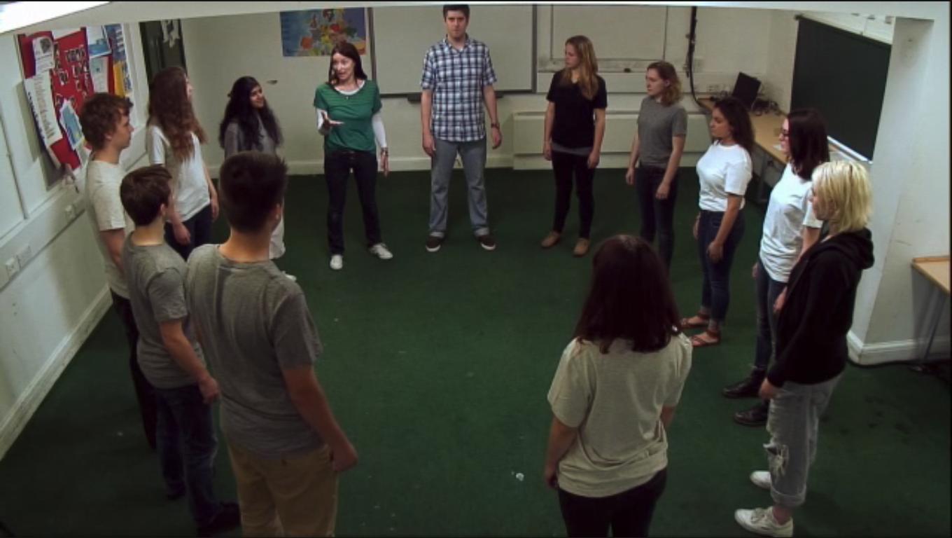 Students and teacher stand in a circle