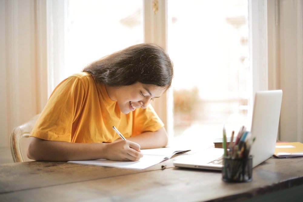 Student writing at desk