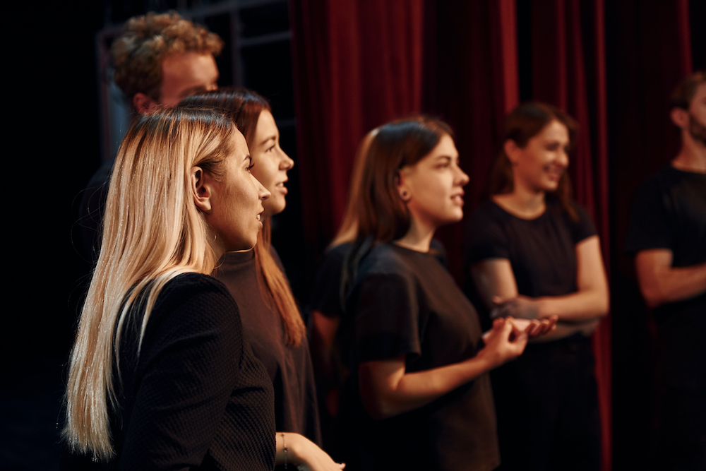 Students and teacher stand on stage