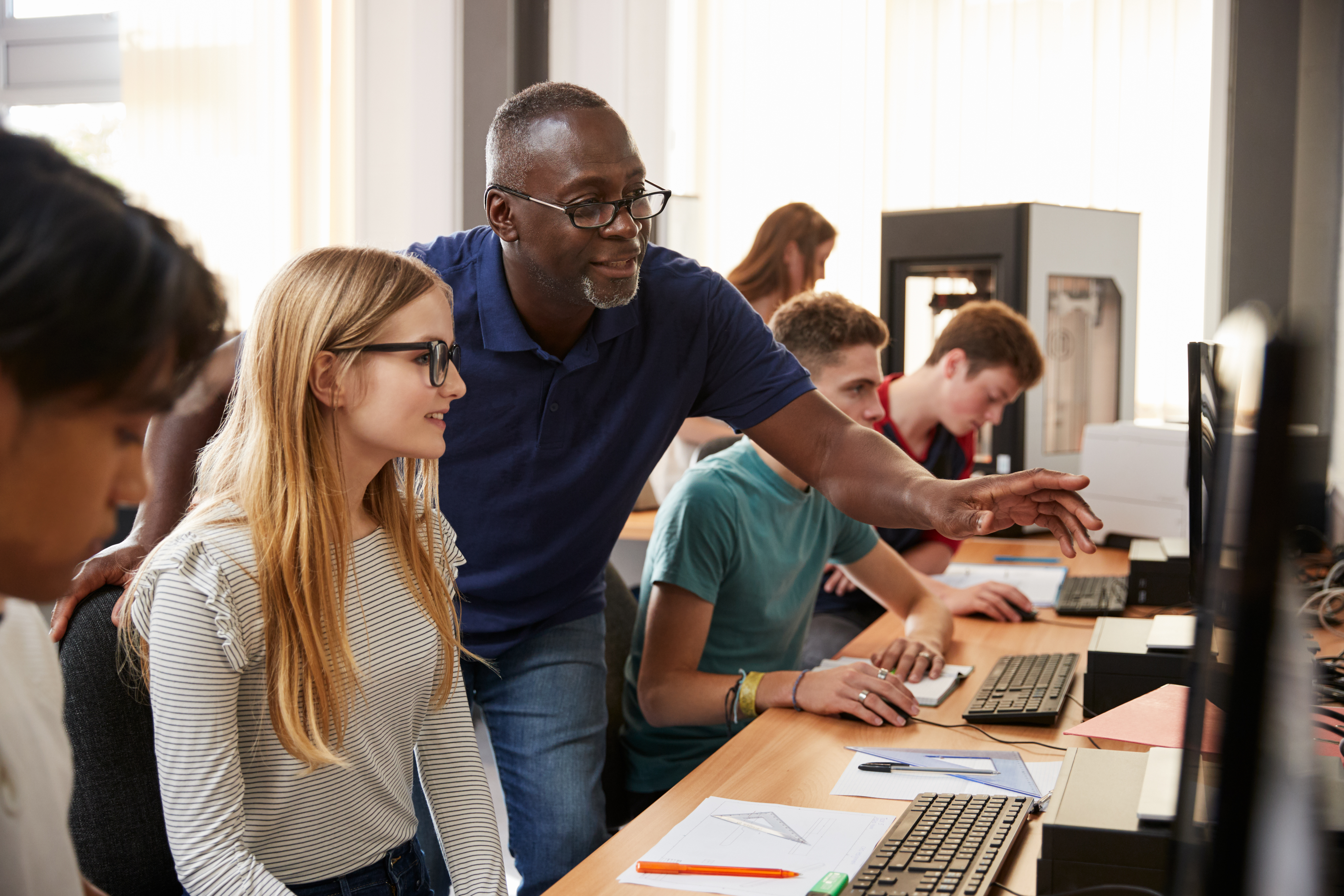 Picture of male teacher pointing to screen of female student